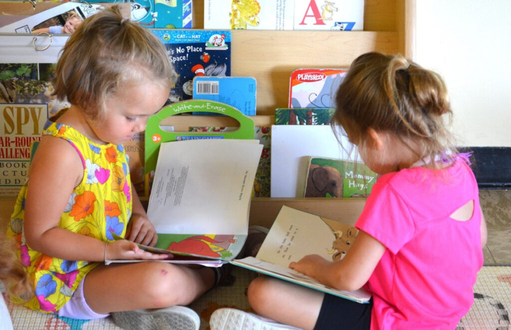 Two girls on the floor reading books